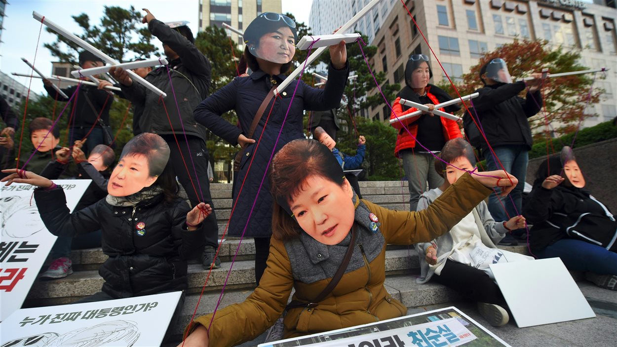 Des manifestants portent des masques à l'effigie de la présidente sud-coréenne Park Geun-hye et de sa confidente Choi Soon-sil à Séoul, le 29 octobre 2016, pour dénoncer un scandale de trafic d'influence impliquant les deux femmes.