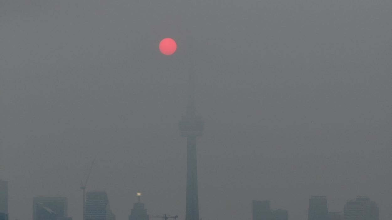 La tour CN sous le smog au lever du soleil.