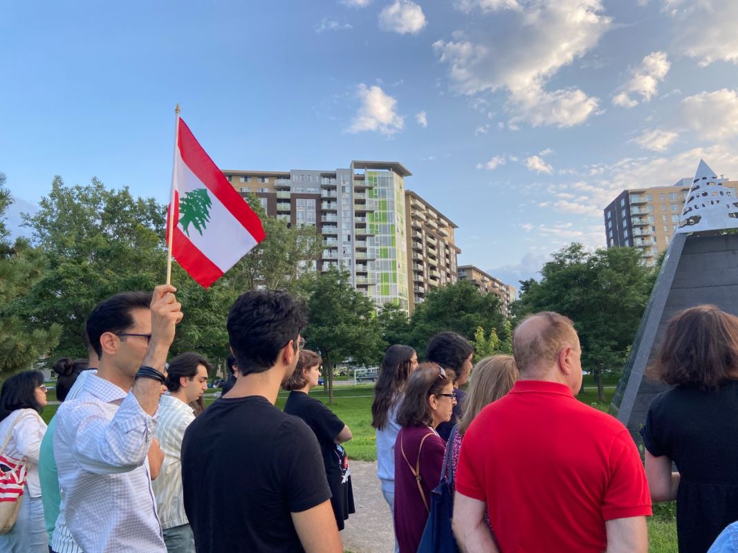 Un homme portant un drapeau libanais au mileu d'un groupe de personnes.