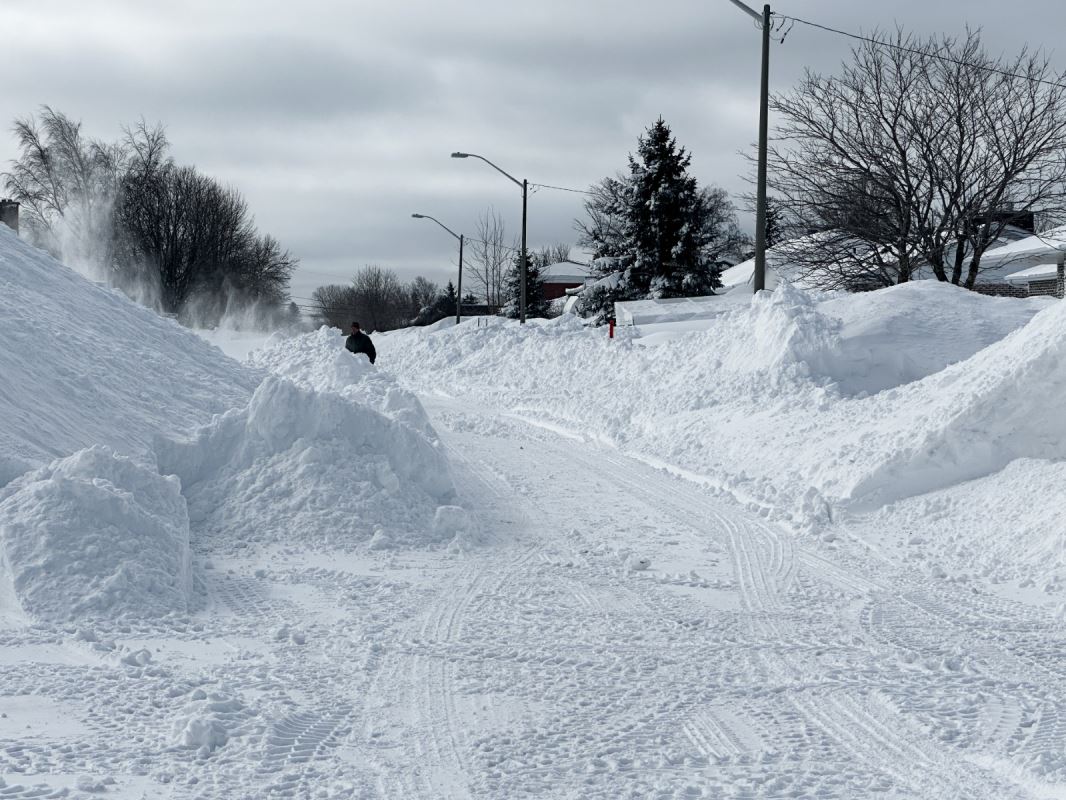 Une rue étroite. D'importants bancs de neige rétrécissent le passage pour les voitures.