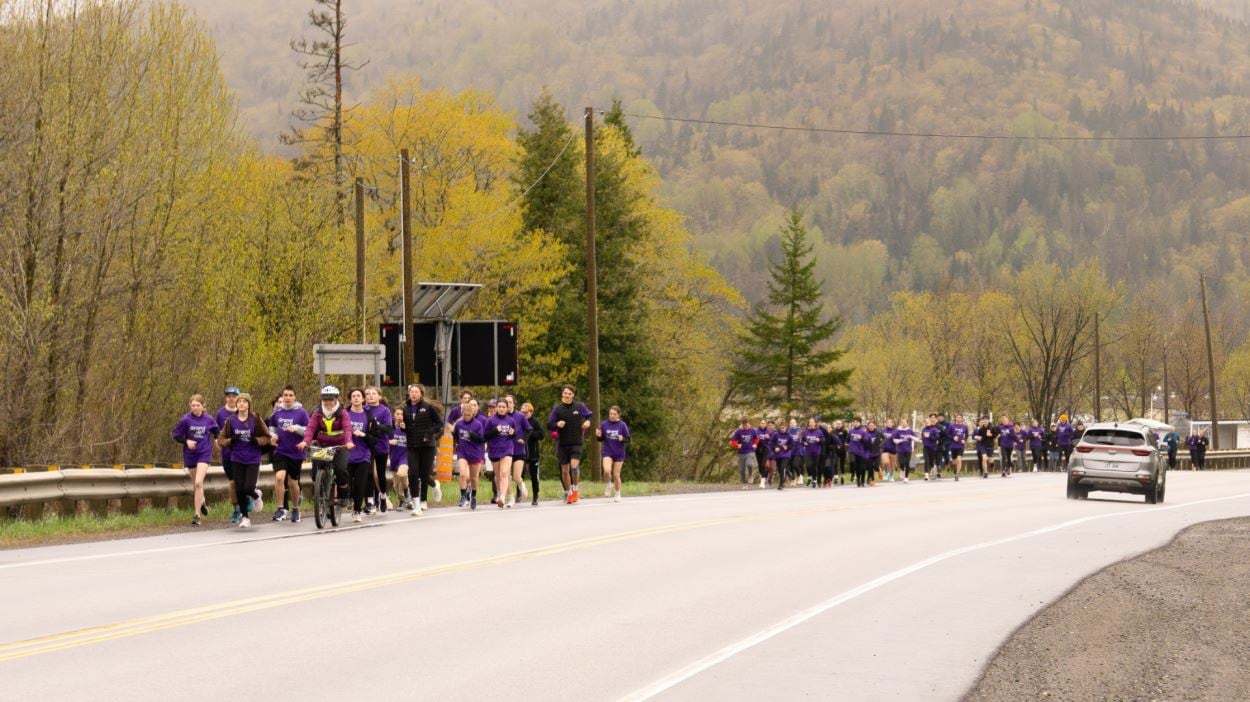 Une foule de jeune court en bordure de route.