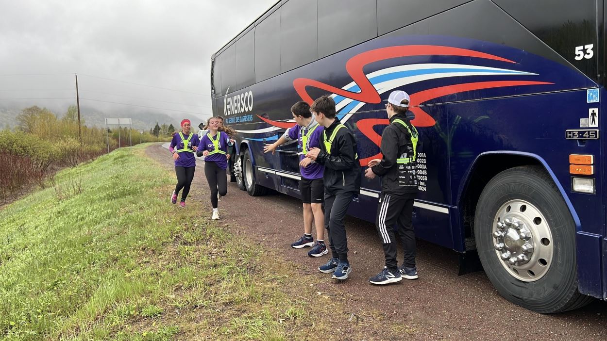 Des coureurs qui passent le témoin près d'un autobus.
