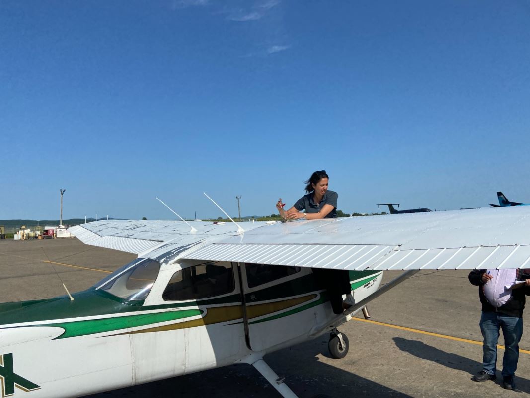 Une femme travaillant sur l'aile d'un petit avion. امرأة تعمل على جناح طائرة صغيرة.