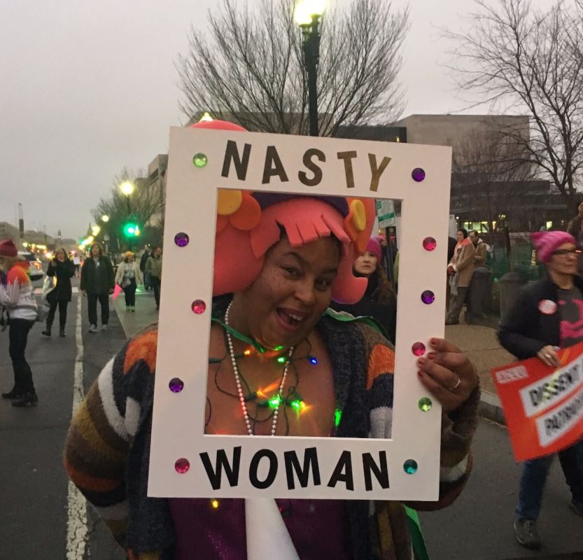 Une femme basanée tient une pancarte.